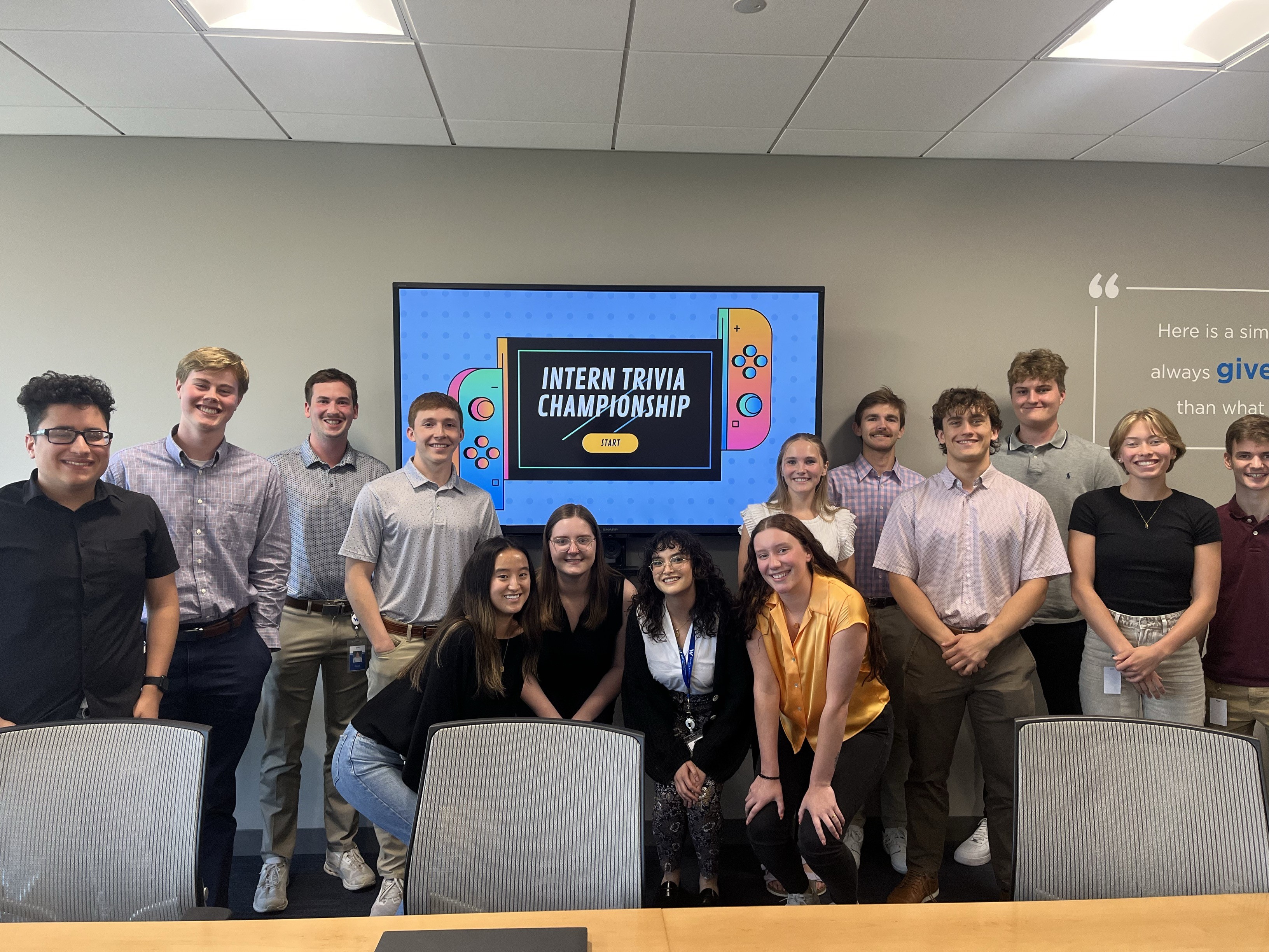 A group of interns standing in front of a tv monitor